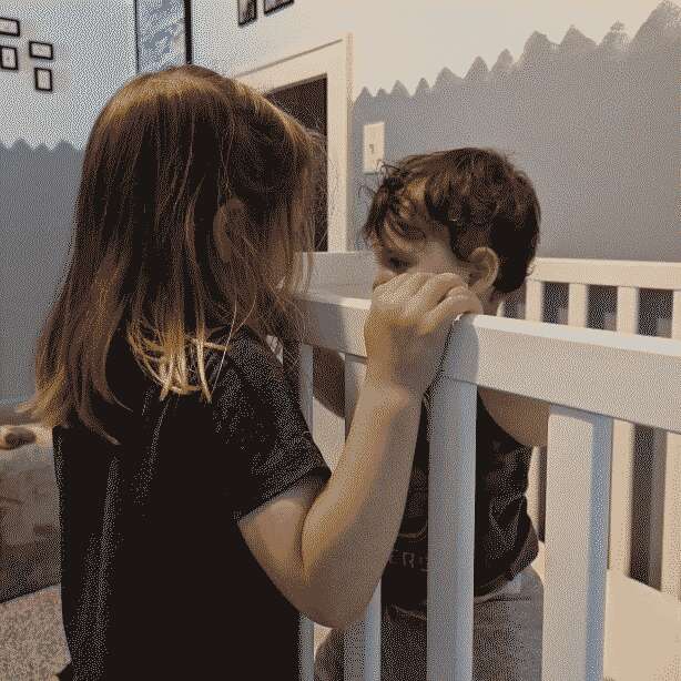 A toddler and a baby standing in front of each other