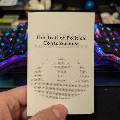My hand holding a zine with the words The Trail of Political Consciousness
and the Rebel Alliance
crest