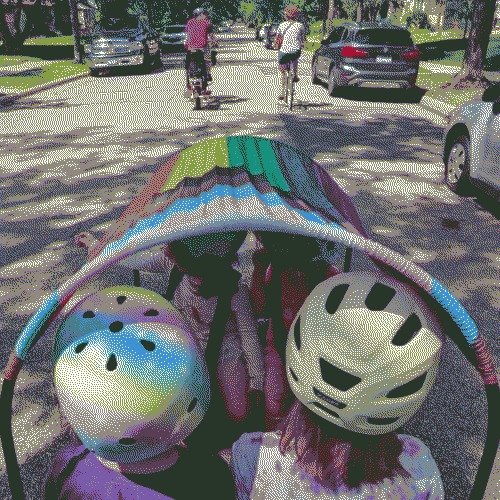 4 kids sitting in the bucket of a cargo bike riding down a street with cars and other bikes around